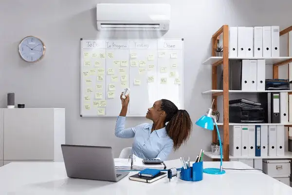 mujer encendiendo su aire acondicionado como parte de la ergonomia en el trabajo